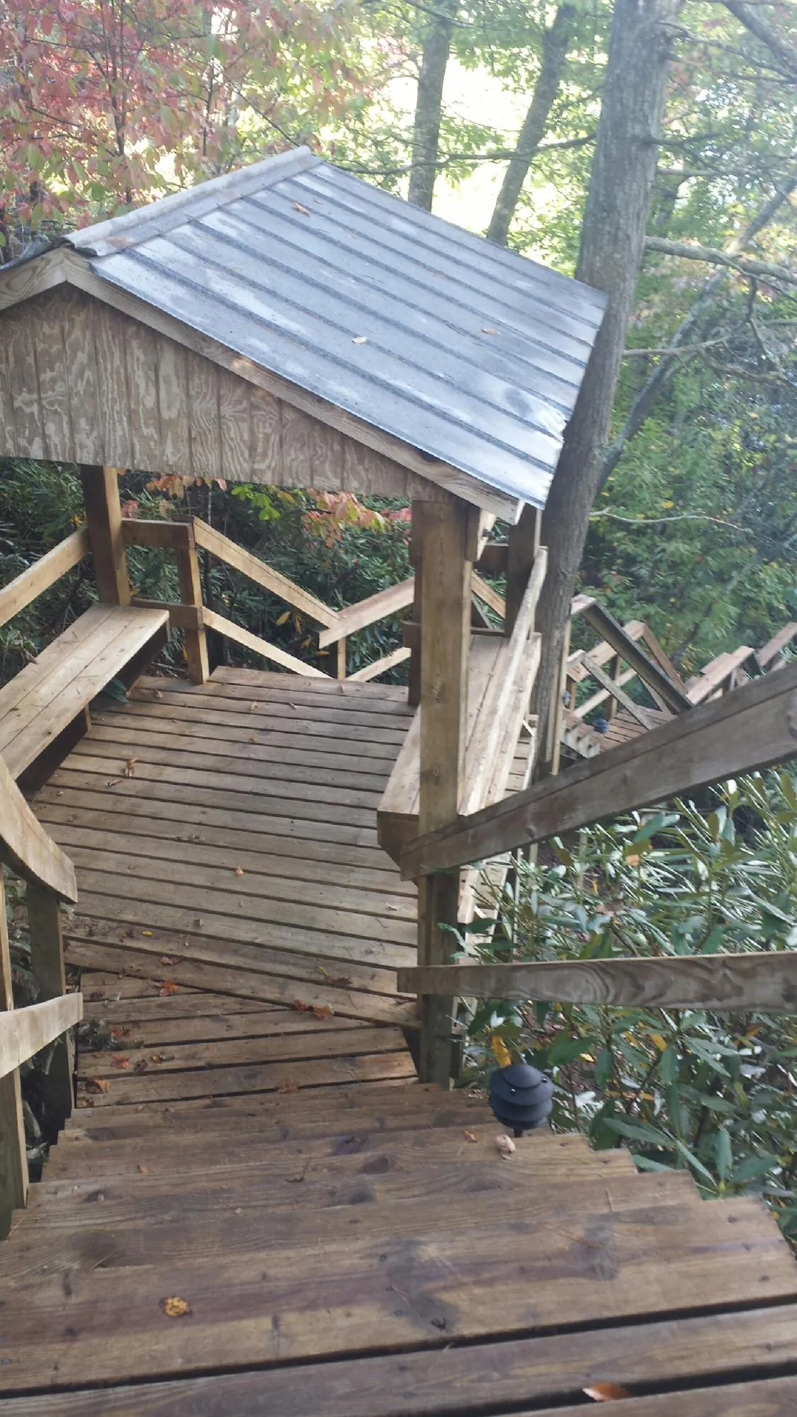 Metal roofed shelter over wooden steps on a wooded walkway — Skylight Repair & Installation work by our crew in Howard